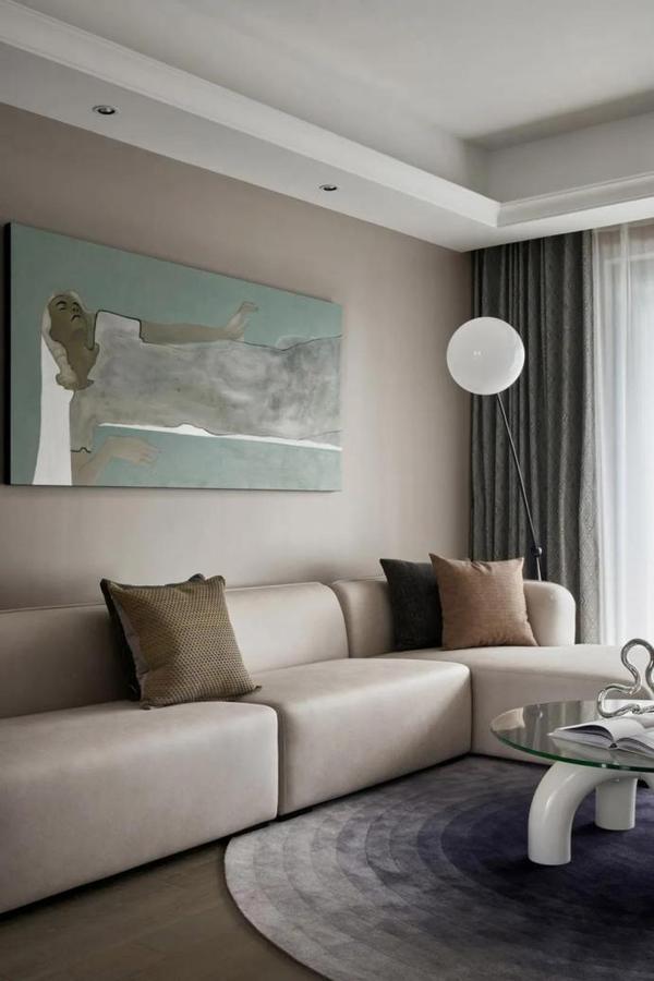 将客厅的白墙改为浅灰褐色,与同色系的沙发组合,用相同色调的抱枕