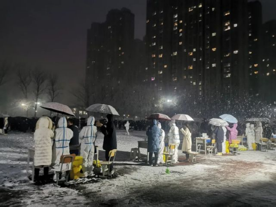 在郑州中原领航实验学校,做核酸的市民自发为医护人员撑伞,他们彼此为