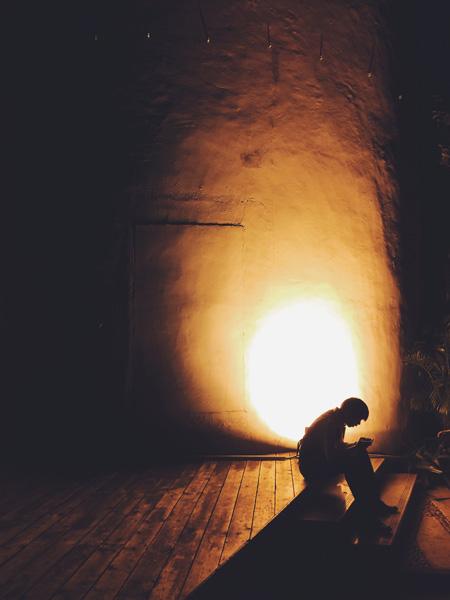 坐在路边的人.背后有一盏地灯,仿佛烛光中的人影.平时会经过的建筑.