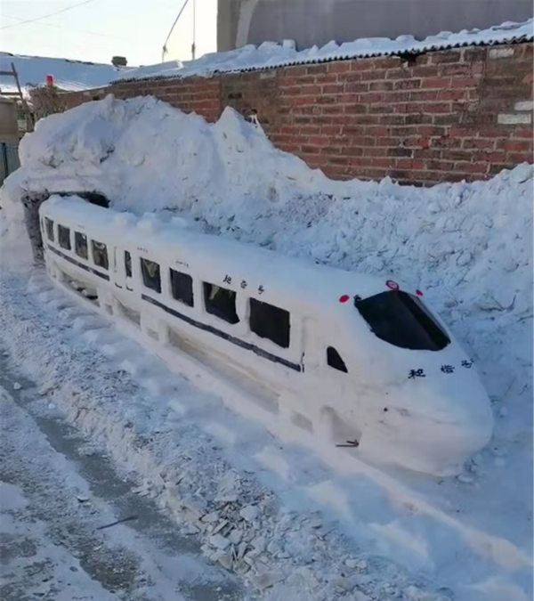 七旬老人陈永江用雪堆出和谐号高铁驶出隧道的雪雕造型,成为这个村