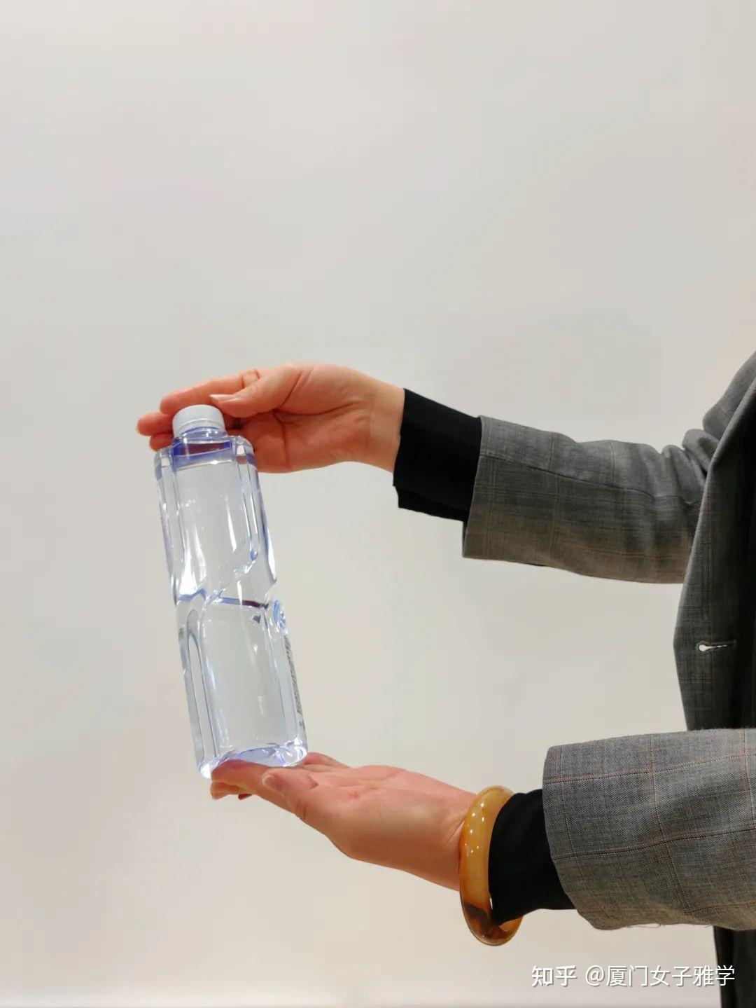 用左手托住矿泉水瓶底,右手轻扶矿泉水瓶盖,把中间的部分留出来给对方