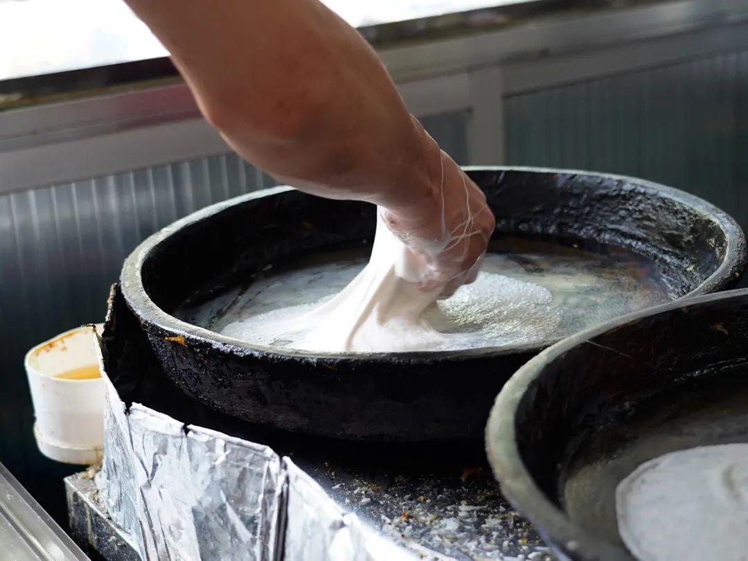 首先将大米打成米浆放在大盆里面用力拍打,使其米浆搅拌均匀,然后将